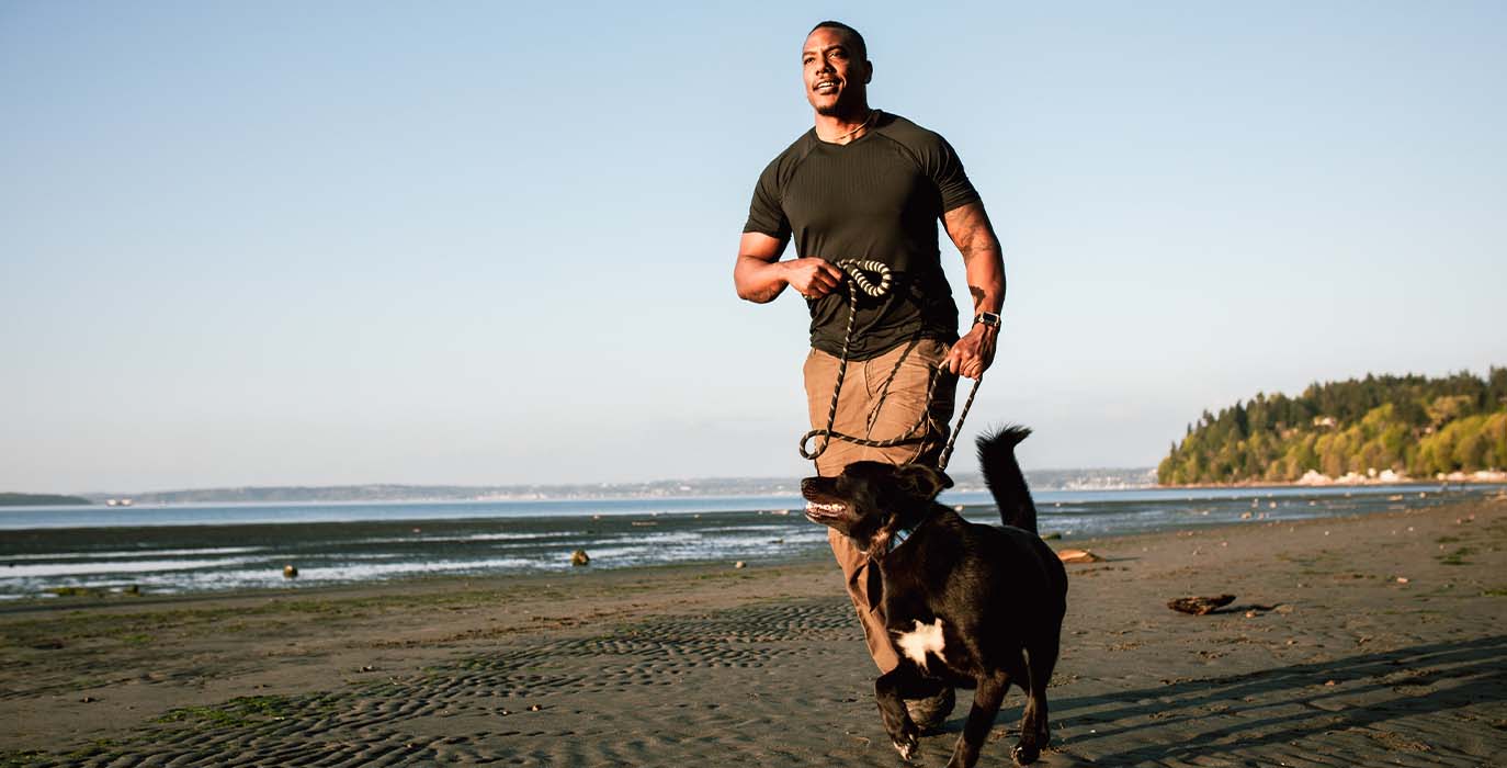 man running with his dog at the beach